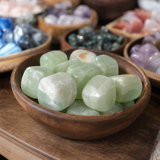 Pistachio Green Calcite  Tumbled Stones in a wooden bowl on a boutique display table