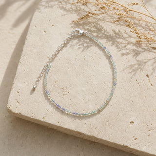 Purple & Green Fluorite bead bracelet resting on a stone slab