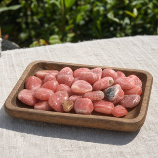 Rhodochrosite E Tumbled Stones in a wooden tray at a market stall