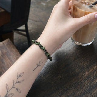 Ruby Zoisite bead bracelet worn on a tattooed forearm holding a coffee