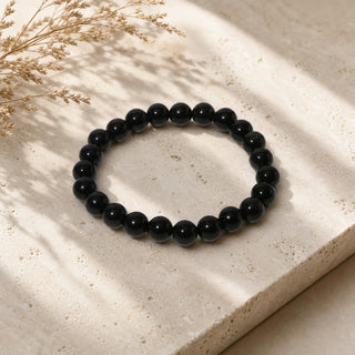 Silver Sheen Obsidian bead bracelet resting on a stone slab