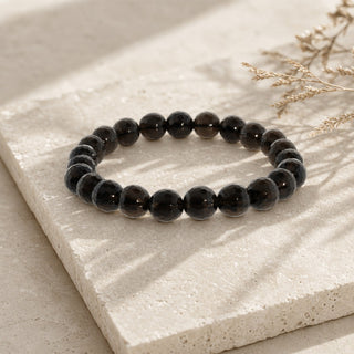 Smoky Quartz bead bracelet resting on a stone slab