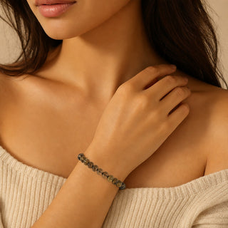 Smoky Quartz bead bracelet worn with the fingertips resting at the collarbone