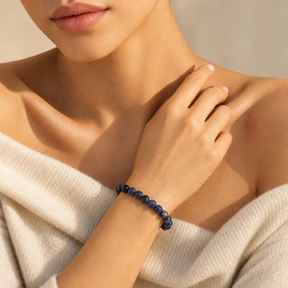 Sodalite bead bracelet worn with the fingertips resting at the collarbone