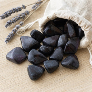 Sugilite E Tumbled #1 spilling from a linen pouch