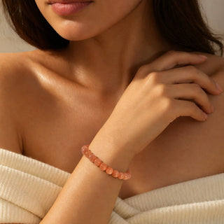 Sunstone bead bracelet worn with the fingertips resting at the collarbone