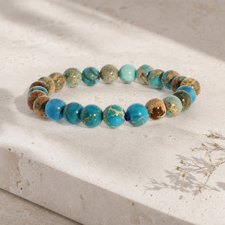Turquoise Impression Jasper bead bracelet resting on a stone slab