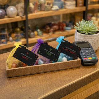 Zodiac Crystal Collection kits in a wooden tray beside the till
